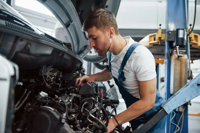 A mechanic working under the hood of a car, representing intelligent insults in action