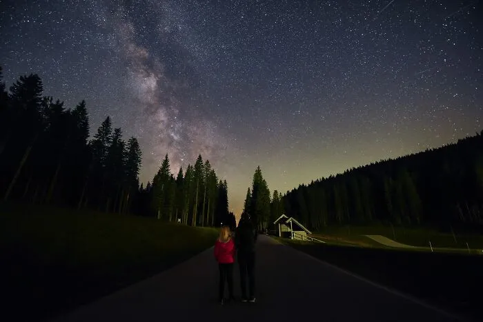 Two people stargazing under the starry night sky, reflecting on intelligent insults.