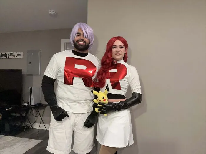 Couple posing together in matching Team Rocket Pokemon Halloween costumes.