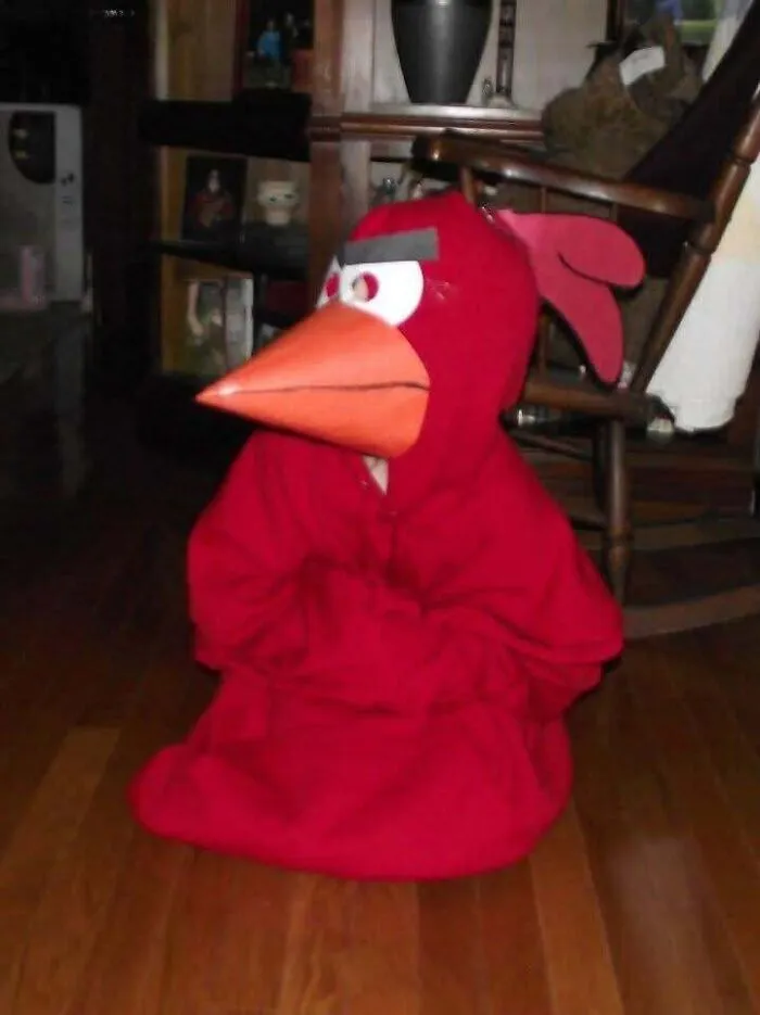 Child sitting indoors wearing a homemade red Angry Bird Halloween costume.