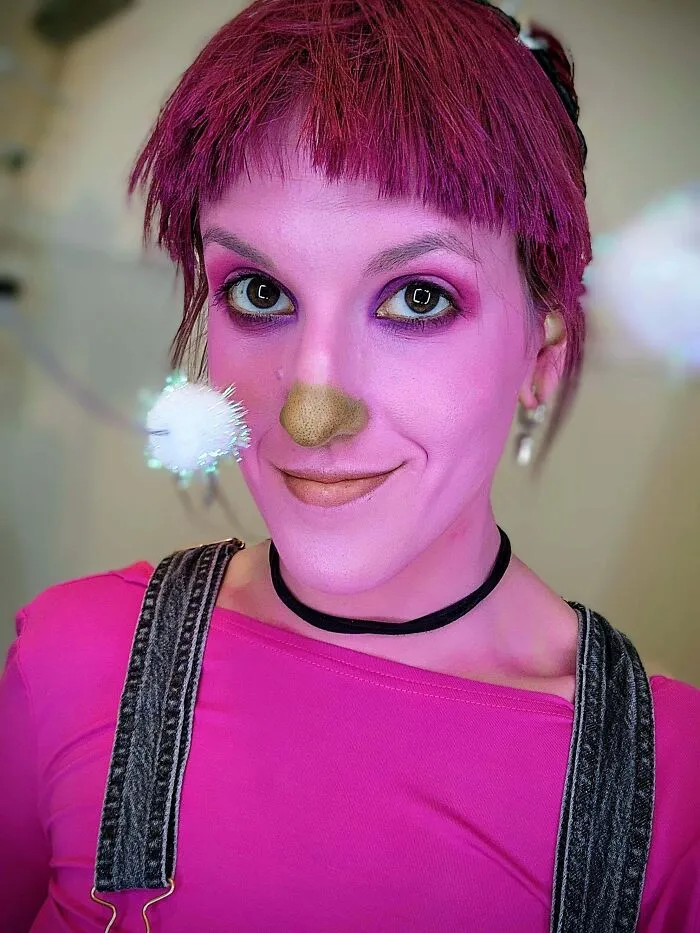 Person with bright pink face makeup and hair dressed in a creative Halloween costume.