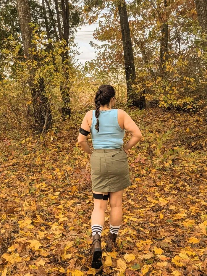 Woman in adventurous outdoor clothing posing in autumn woods for Halloween costumes.
