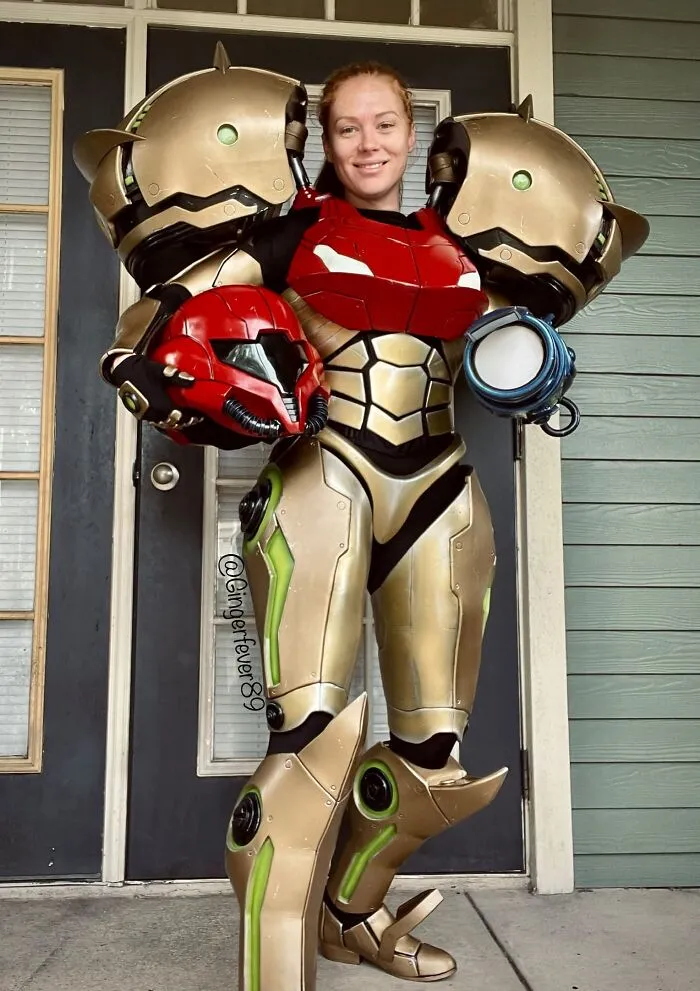 Woman posing in a detailed Samus Aran futuristic armor Halloween costume.