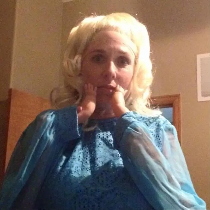 Woman in a blue dress wearing small hand props for a funny Halloween costume idea.
