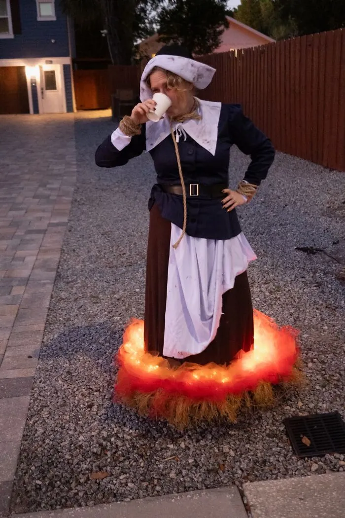 A woman dressed in a creative illuminated witch trial Halloween costume outdoors.