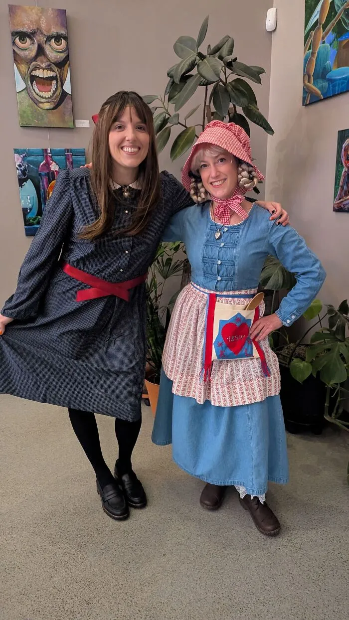 Two women wearing retro and vintage dresses showing off their creative Halloween costumes.