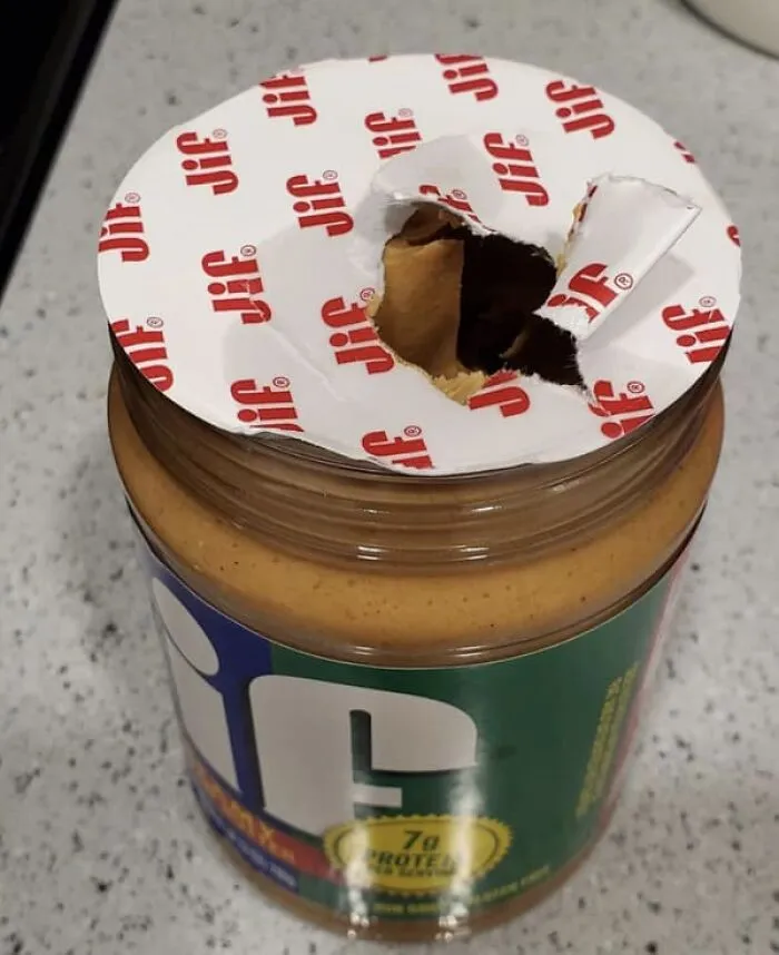 A peanut butter jar with a hole poked through the seal, showing annoying roommate stories.