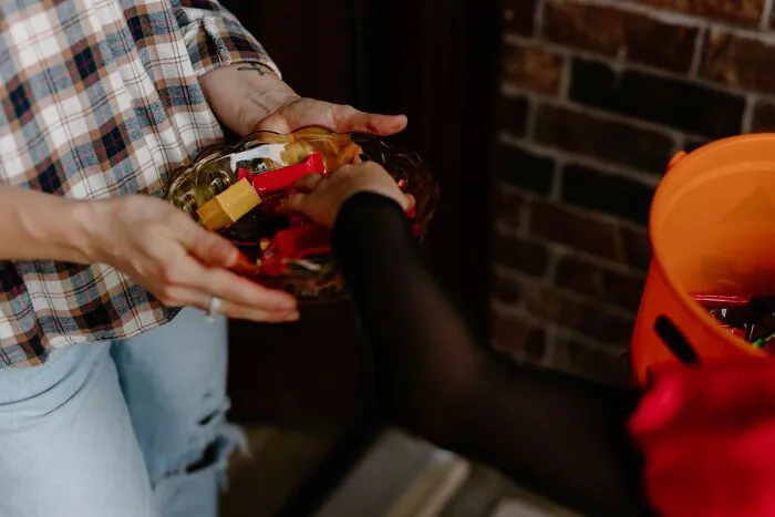 Hands reaching for candies in a bowl during Halloween trick-or-treating.