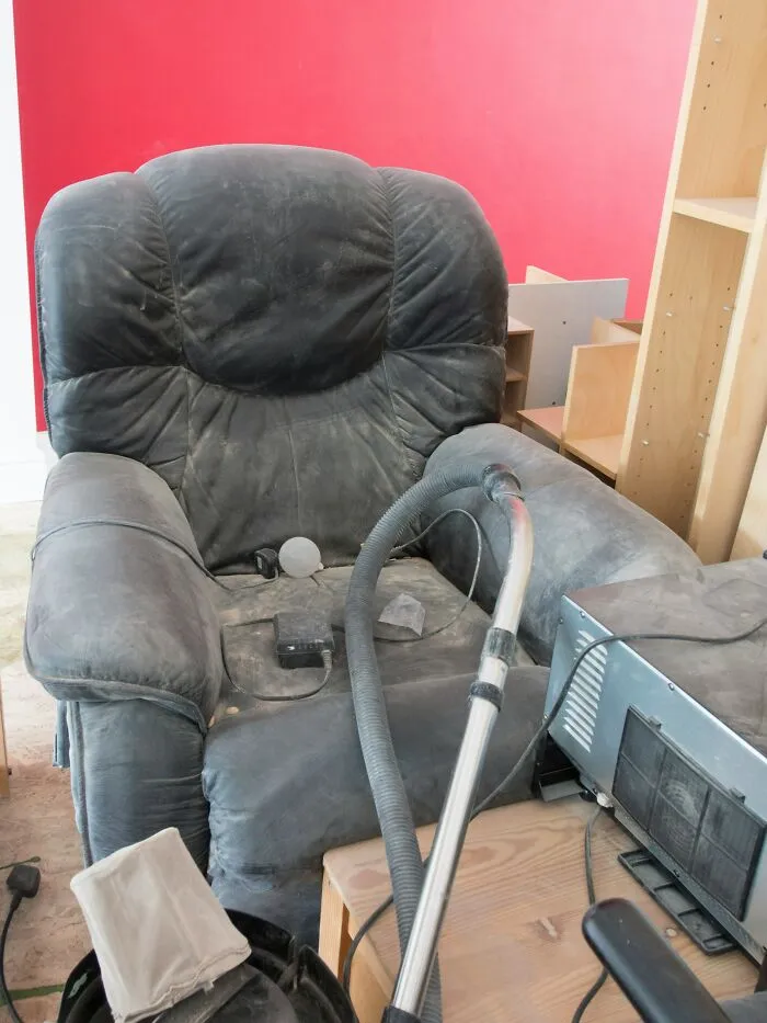 A dusty armchair and vacuum cleaner representing wild stories about household cleaning tasks.