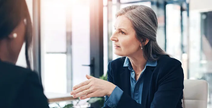 A serious businesswoman talking intently to a colleague about difficult situations in people's jobs
