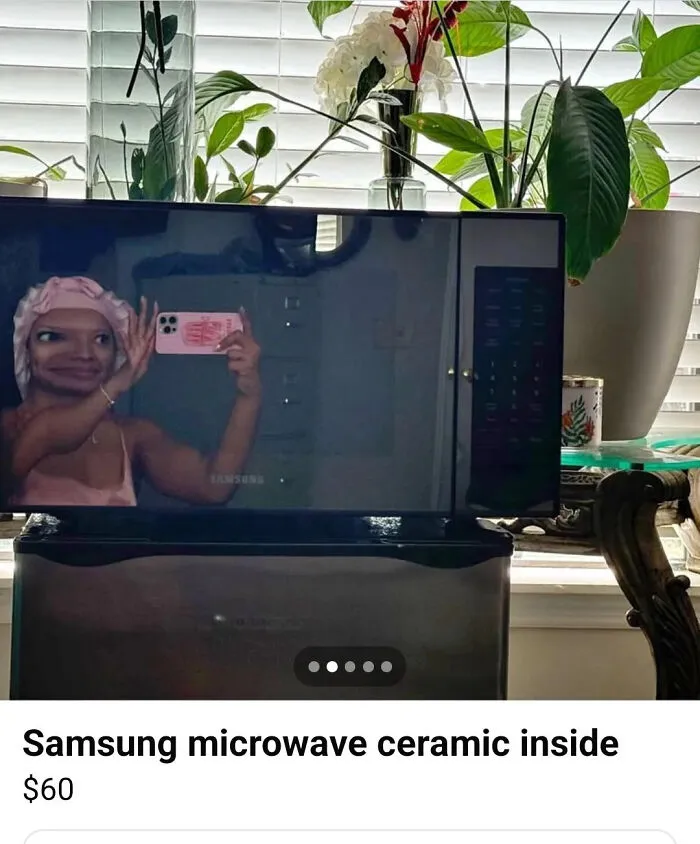 Funny reflection in a microwave door showing a distorted face taking a selfie.
