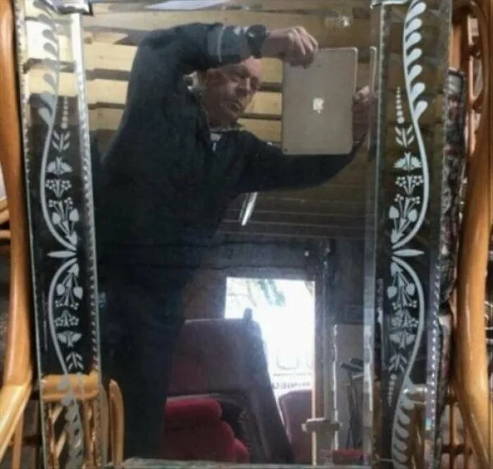 Funny mirror pics showing a man taking an awkward tablet photo in an ornate mirror reflection