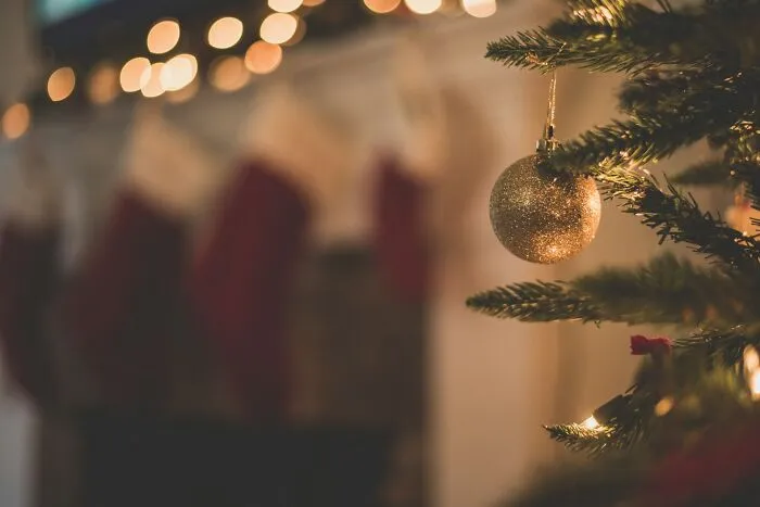 Christmas tree branch with a shiny golden bauble ornament reflecting holiday infidelity stories context