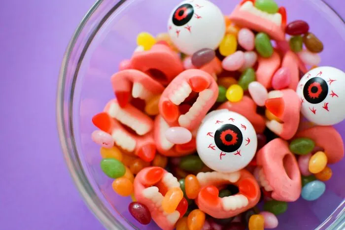 A glass bowl filled with scary gummy teeth and eyeballs, representing Halloween conflicts over spooky party snacks.