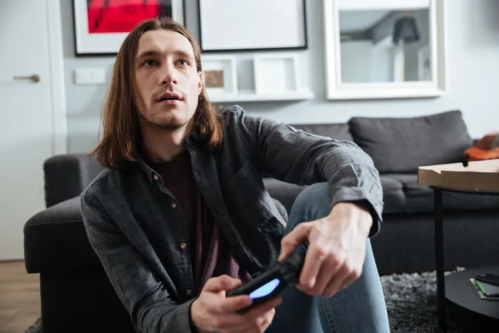 A young man holding a game controller with a shocked look, representing stories of being disowned.