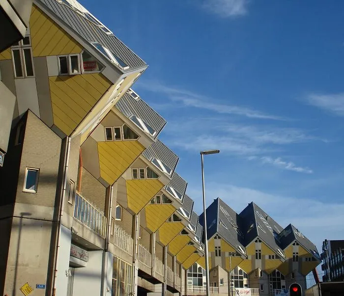 Unique cube houses with tilted yellow walls and triangular roofs under blue sky