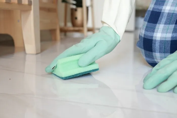 A person wearing rubber gloves scrubbing a tiled floor in wild Airbnb stories