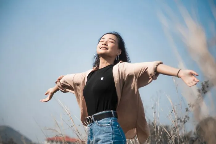 A woman standing outdoors with outstretched arms feeling relieved from bad Airbnb stories