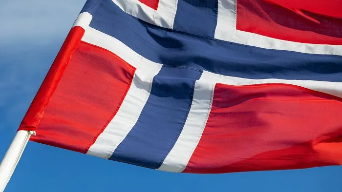 Close-up of the Norwegian flag waving against a blue sky, related to unique Airbnb Stories.