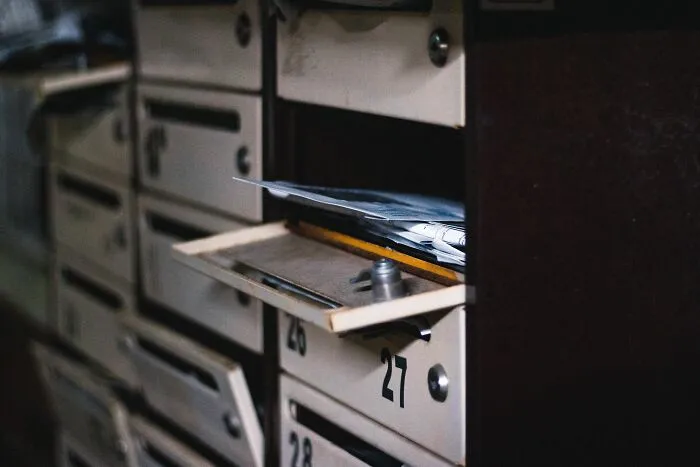 Open apartment mailboxes filled with mail, illustrating Airbnb host and rental challenges.