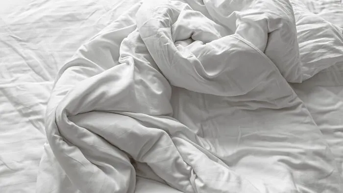 An unmade bed with a messy white duvet, related to challenging Airbnb host experiences.