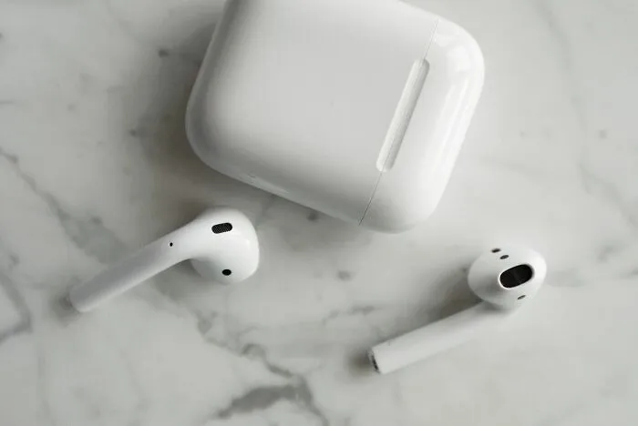 Pair of white wireless earbuds left behind, illustrating funny Airbnb Stories