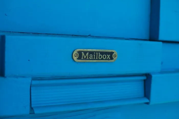 A close-up of a blue door mailbox slot, representing guest communication in Airbnb stories.