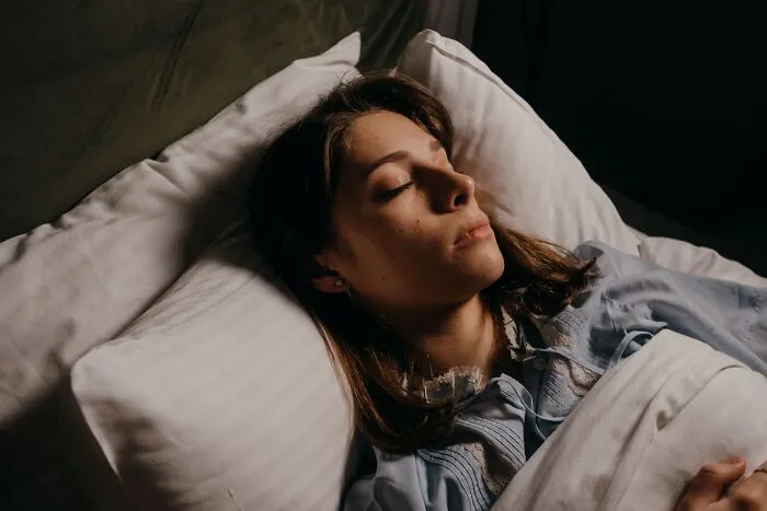 A woman sleeping in bed, capturing spooky things people experienced during scary late night moments.
