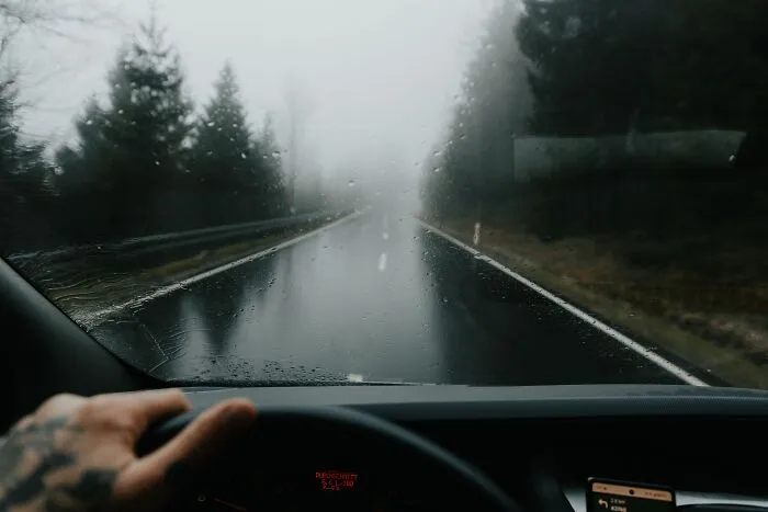 Driver view through a rain-covered windshield on a foggy forest road, showing spooky things people experienced