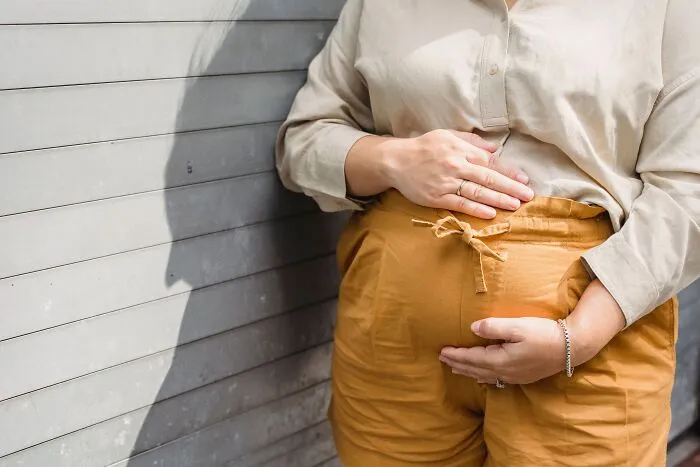 A pregnant woman holding her stomach while standing outside, illustrating spooky things people experienced
