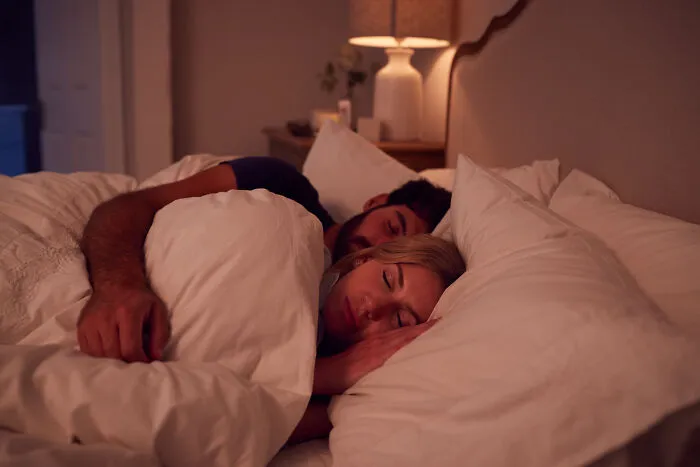 A couple sleeping comfortably together in bed at night, capturing spooky things people experienced while resting