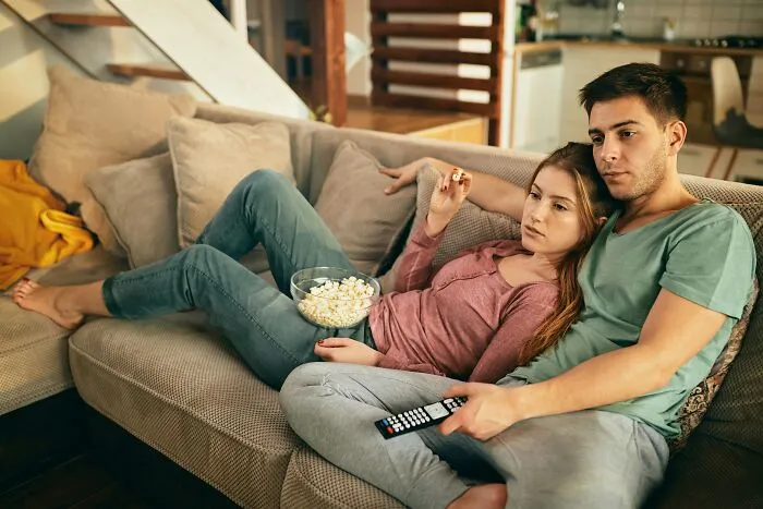 A couple watching a movie together on a sofa in a dimly lit room