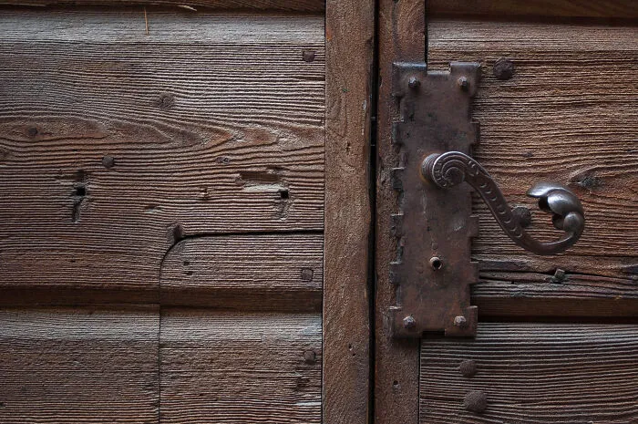 Close up of an antique wooden door with a metallic handle creating a spooky vintage feel