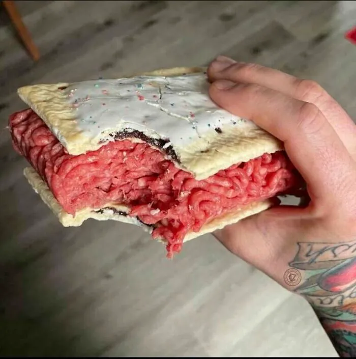 A hand holding a Pop-Tart filled with raw ground meat as an example of cursed images.