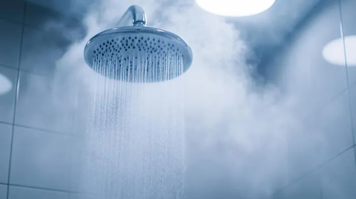 Close-up of showerhead with steaming hot water spraying