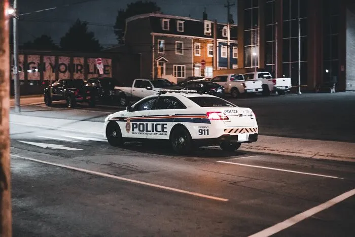 Police car parked at night on urban street with buildings