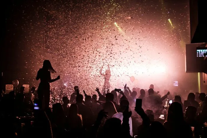 Crowd enjoying a party with confetti and vibrant lighting effects
