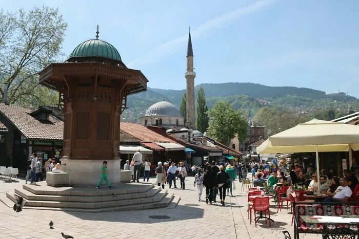 Birds eye market square with mosque minaret and crowd under blue sky