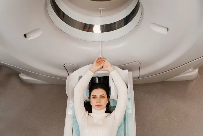 A patient lying on an MRI scanner bed feeling sick during an imaging scan