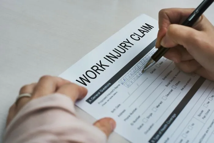 A person filing out a work injury claim form, revealing behind the scenes details at companies people trust.
