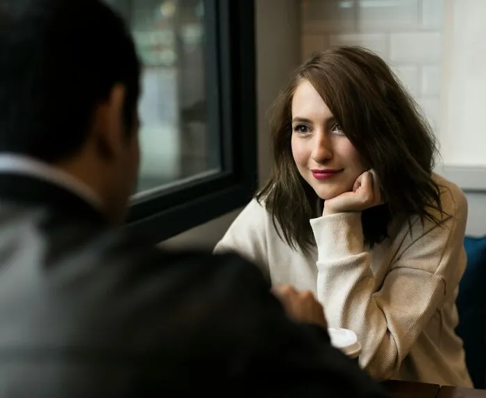 A couple sitting together at a table engaged in conversation about relationships and infidelity stories.