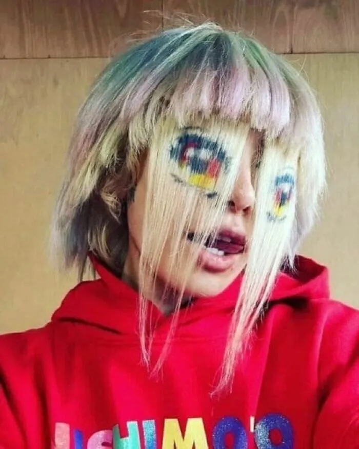 Person with hair styled and painted to look like cartoon eyes on their face