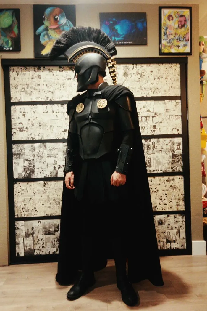 A person in full black Spartan warrior armor, displaying a creative Halloween costume idea.