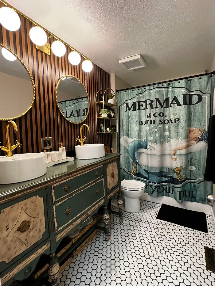 Vintage bathroom home makeover featuring double sinks, gold fixtures, and a mermaid shower curtain