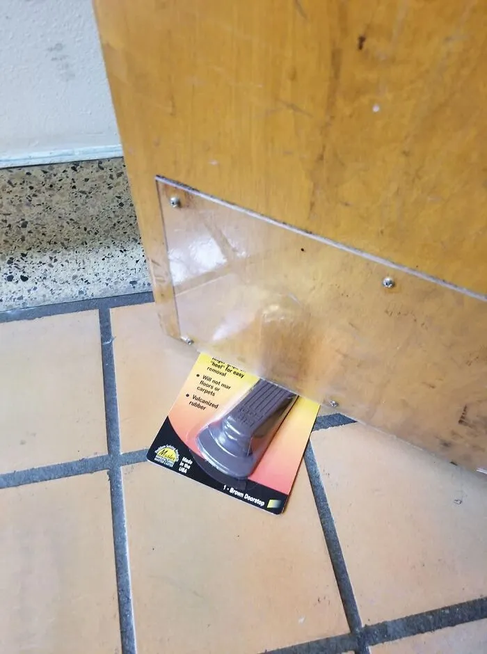 A door wedged open using a brown doorstop that is still in its plastic packaging, one of many absurd products.