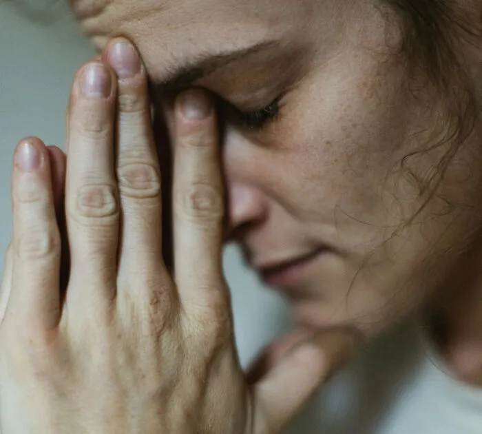 A close up shot of a stressed person pinching the bridge of their nose after a funny fail.