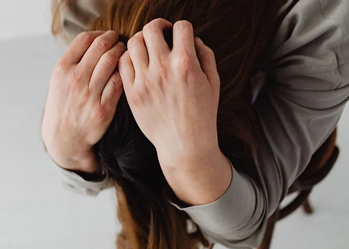 Overhead view of a person holding their head in frustration while solving strange online mysteries.