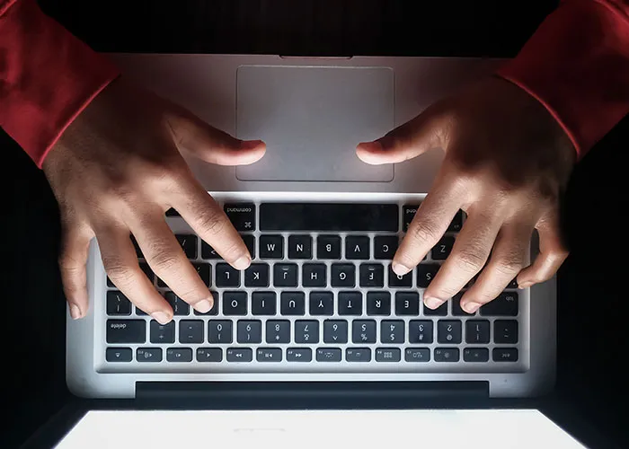 Top-down shot of a person typing on a laptop keyboard late at night exploring strange online mysteries.