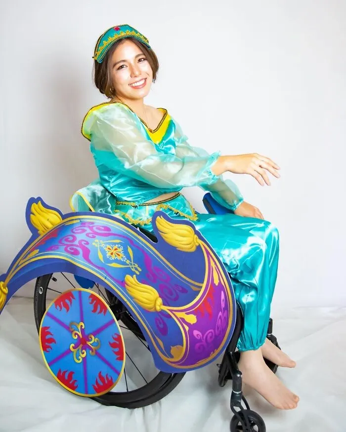 A woman dressed as Princess Jasmine in a wheelchair decorated like a magic carpet for Halloween.