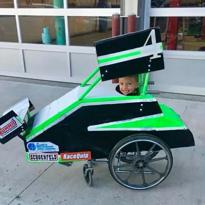 Young boy smiling in a race car wheelchair costume created for creative people with disabilities.